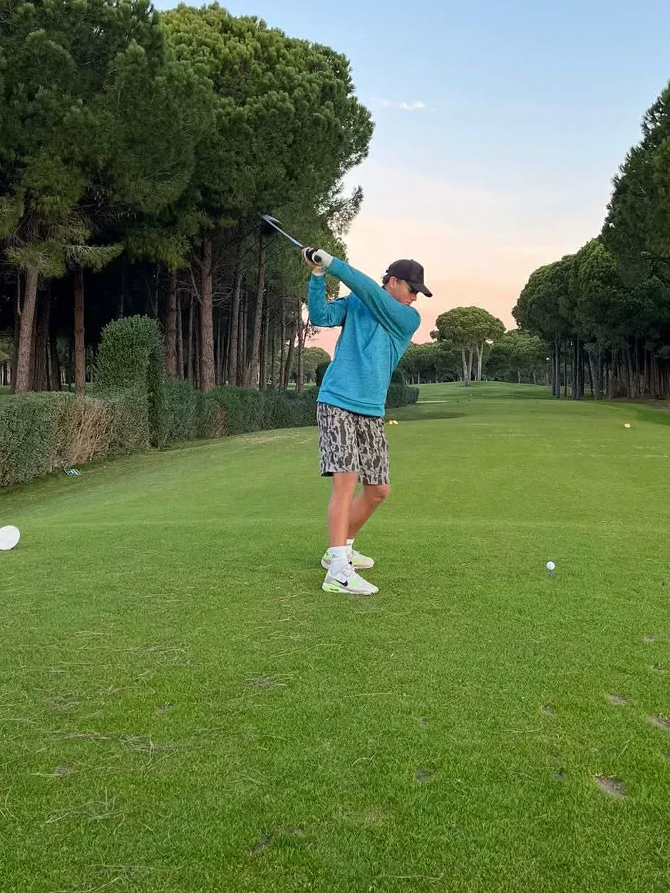 Matyáš v backswingu na golfovém hřišti za soumraku